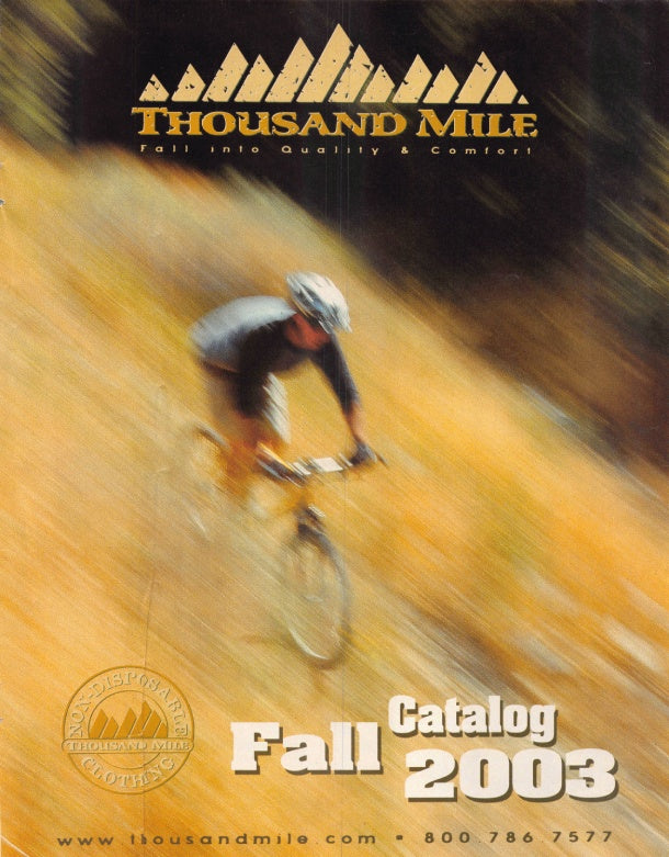 Cover of the Thousand Mile Fall Catalog 2003, featuring a blurred mountain biker on a dirt trail with the Thousand Mile logo at the top and catalog title at the bottom.